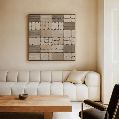 a modern living room with a large abstract artwork hanging on the wall above a white sofa. The sofa is positioned in front of a wooden coffee table, and a black leather chair is situated in the corner of the room.