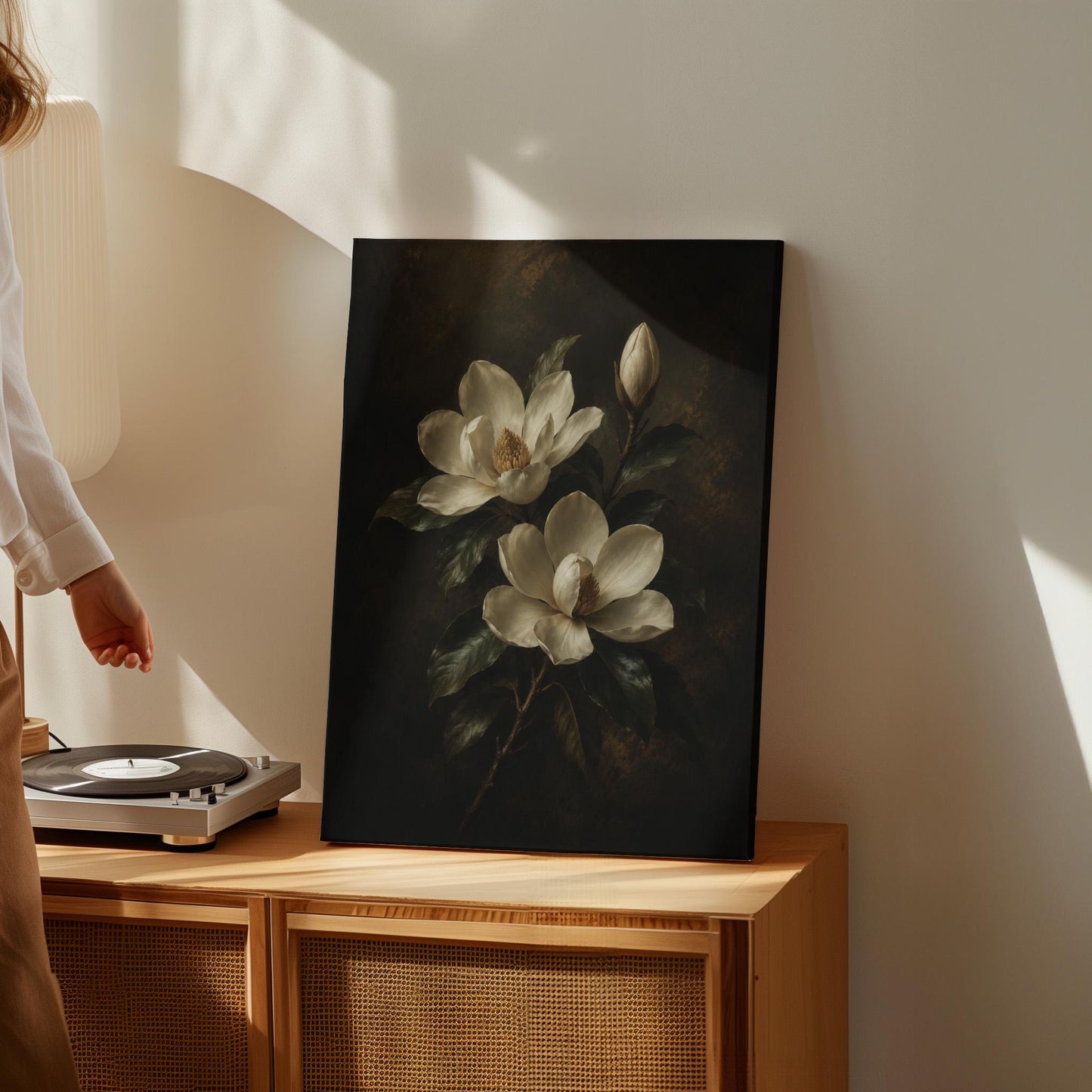 Cream magnolia blooms and dark glossy leaves, canvas print displayed on a neutral wall in a styled interior
