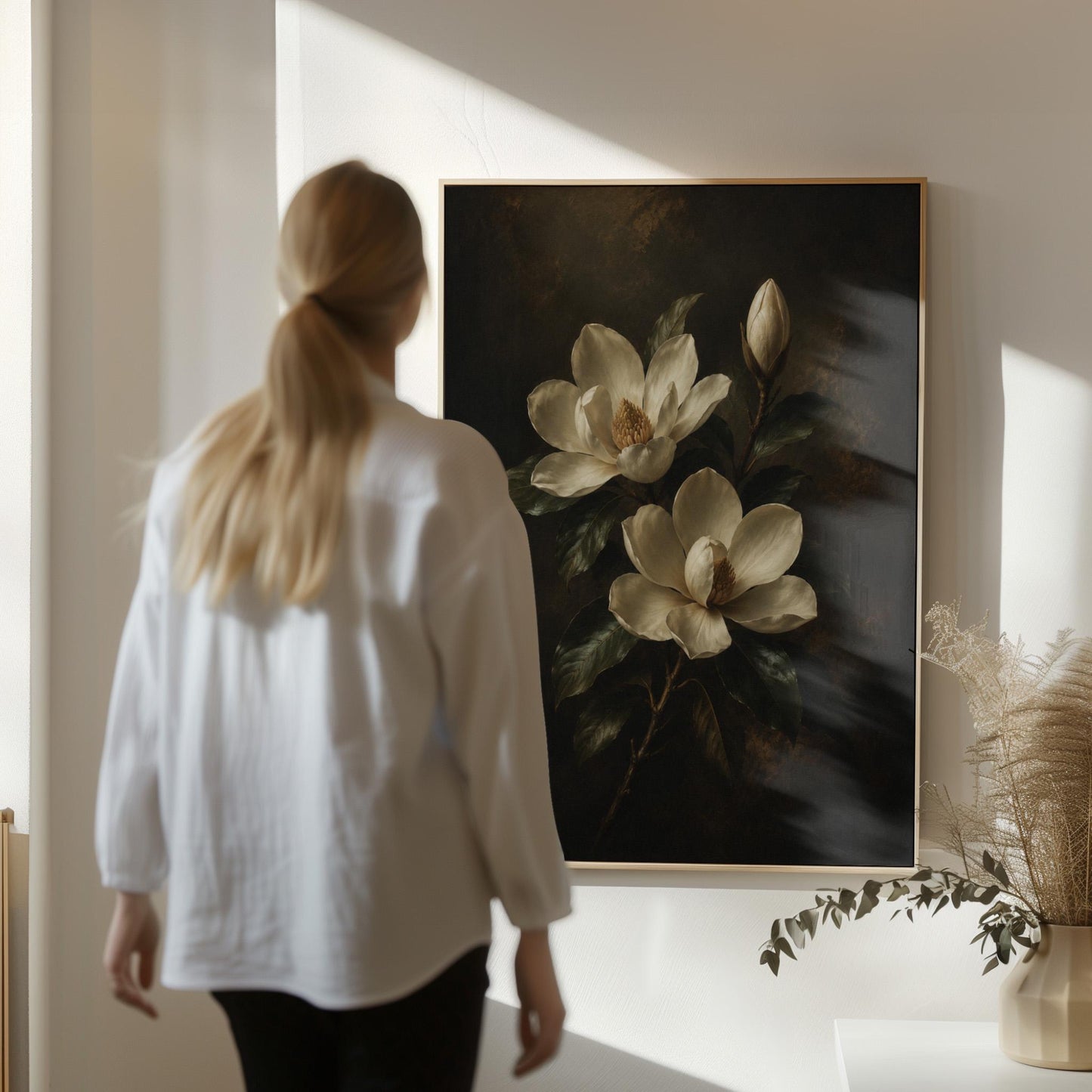 Cream magnolia blooms and dark glossy leaves, canvas wall art hanging in a calm, modern living space