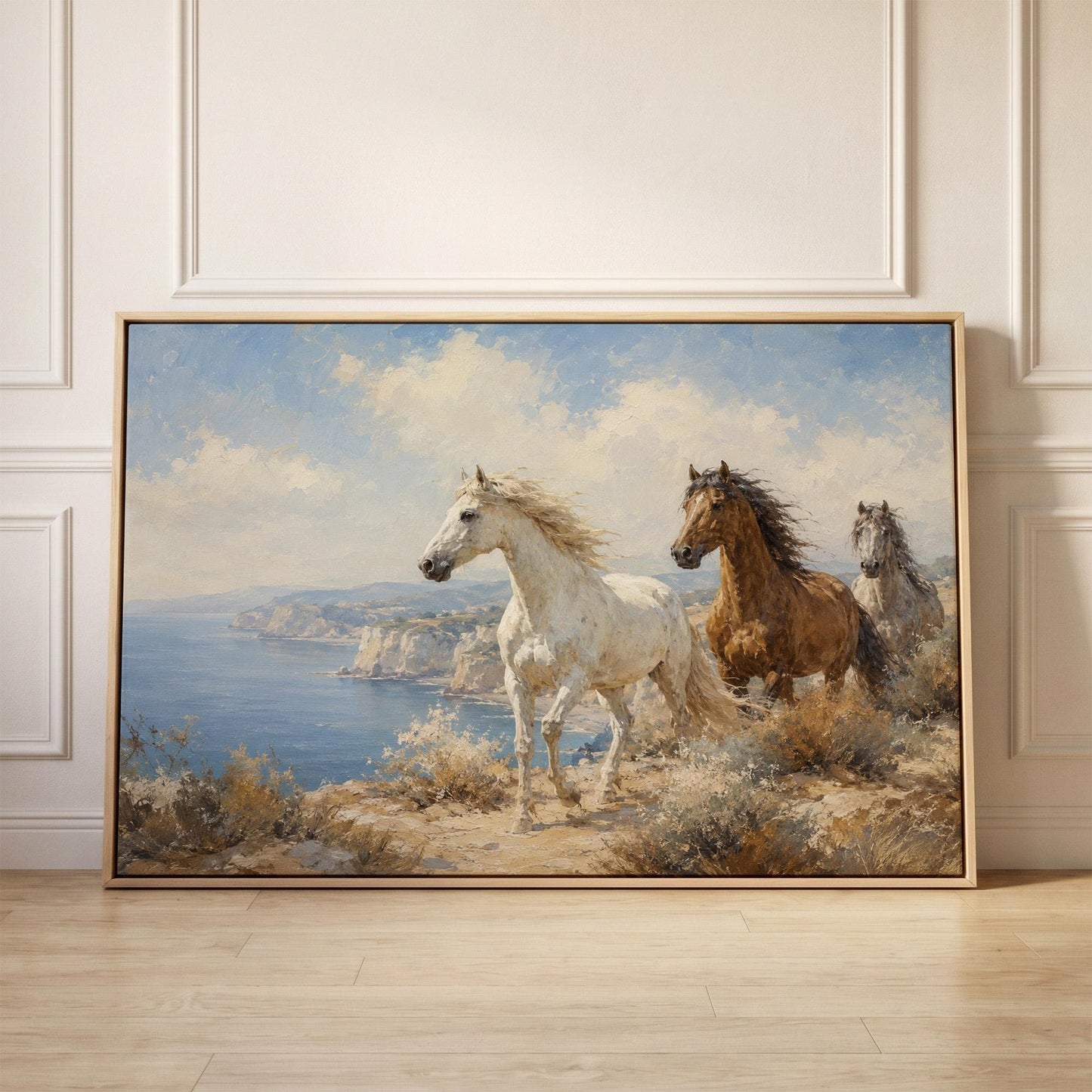 Three horses on a coastal bluff above a blue sea, canvas print held up against a sunlit bedroom wall
