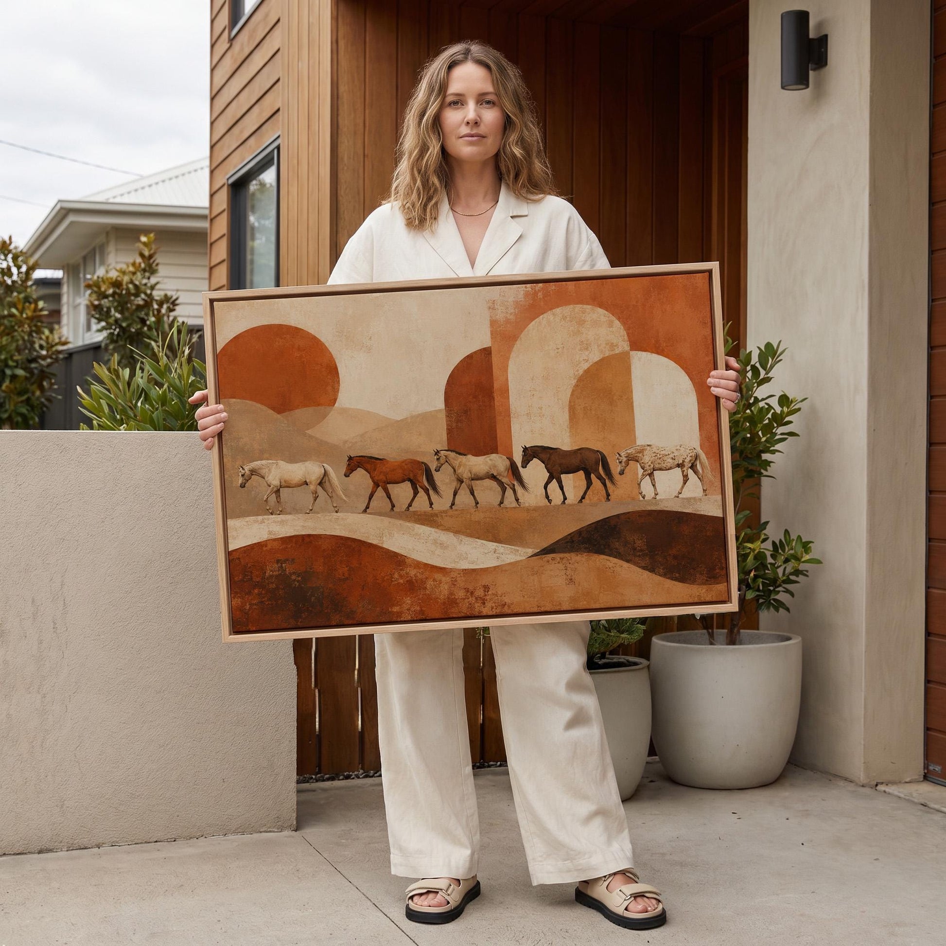 Line of horses crossing an abstract terracotta landscape, canvas print hanging in a calm, modern living space