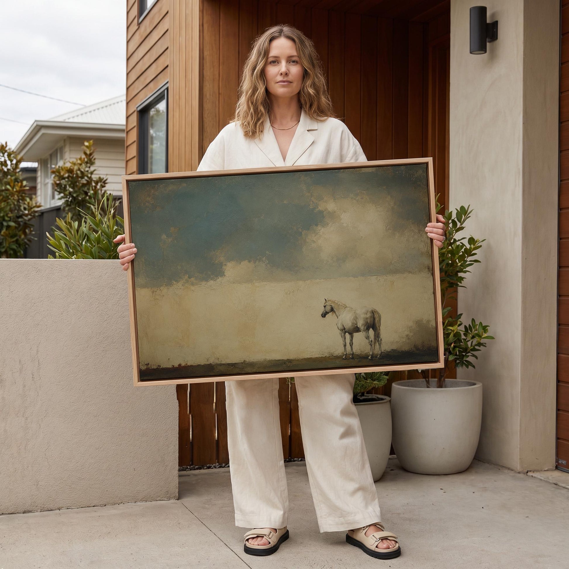 Pale horse alone in a minimalist blue and beige landscape, canvas print shown to scale in a furnished room