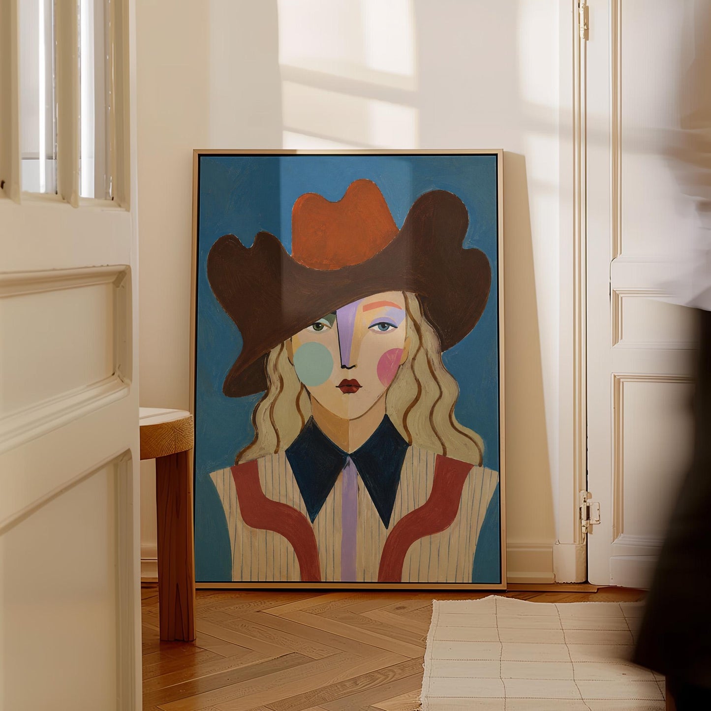 Blonde cowgirl in a rust cowboy hat with a cubist face on deep blue, canvas print hanging in a calm, modern living space