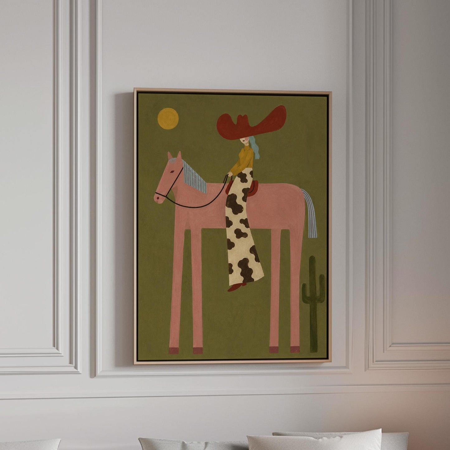 Cowgirl in a red hat riding a long-legged pink horse past a cactus at sunset, canvas print in a bright room with natural daylight
