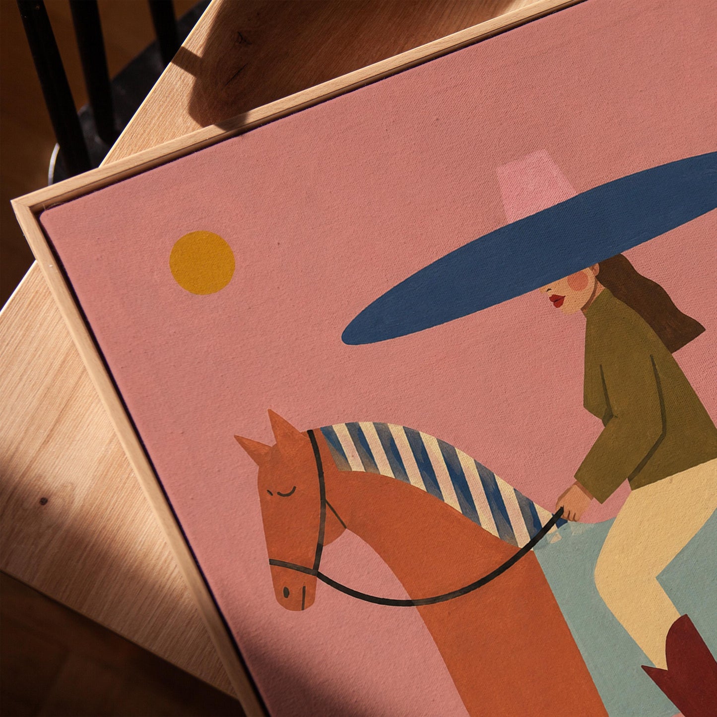 Woman in a wide navy hat riding a chestnut horse in profile on coral pink, canvas print in a warm, minimally styled interior