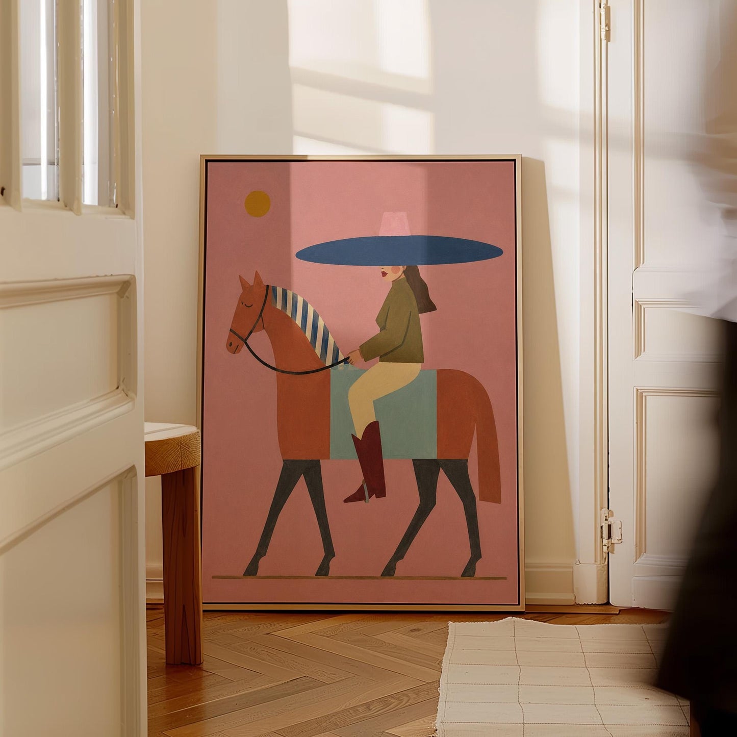 Woman in a wide navy hat riding a chestnut horse in profile on coral pink, canvas print on a quiet wall in a considered interior