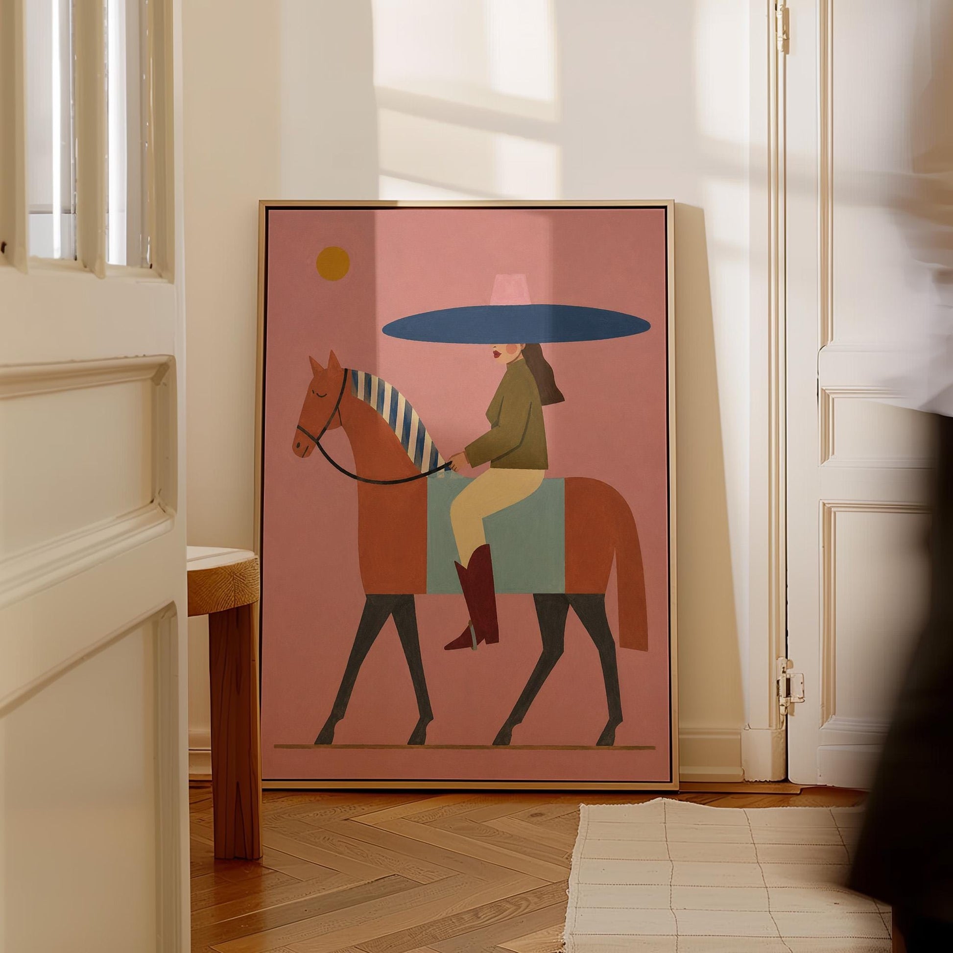 Woman in a wide navy hat riding a chestnut horse in profile on coral pink, canvas print on a quiet wall in a considered interior