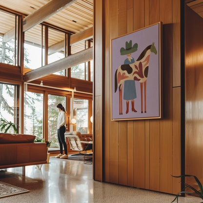 Cowgirl in a green hat beside a tall patterned horse on soft lilac, canvas print seen in a warm interior with natural light