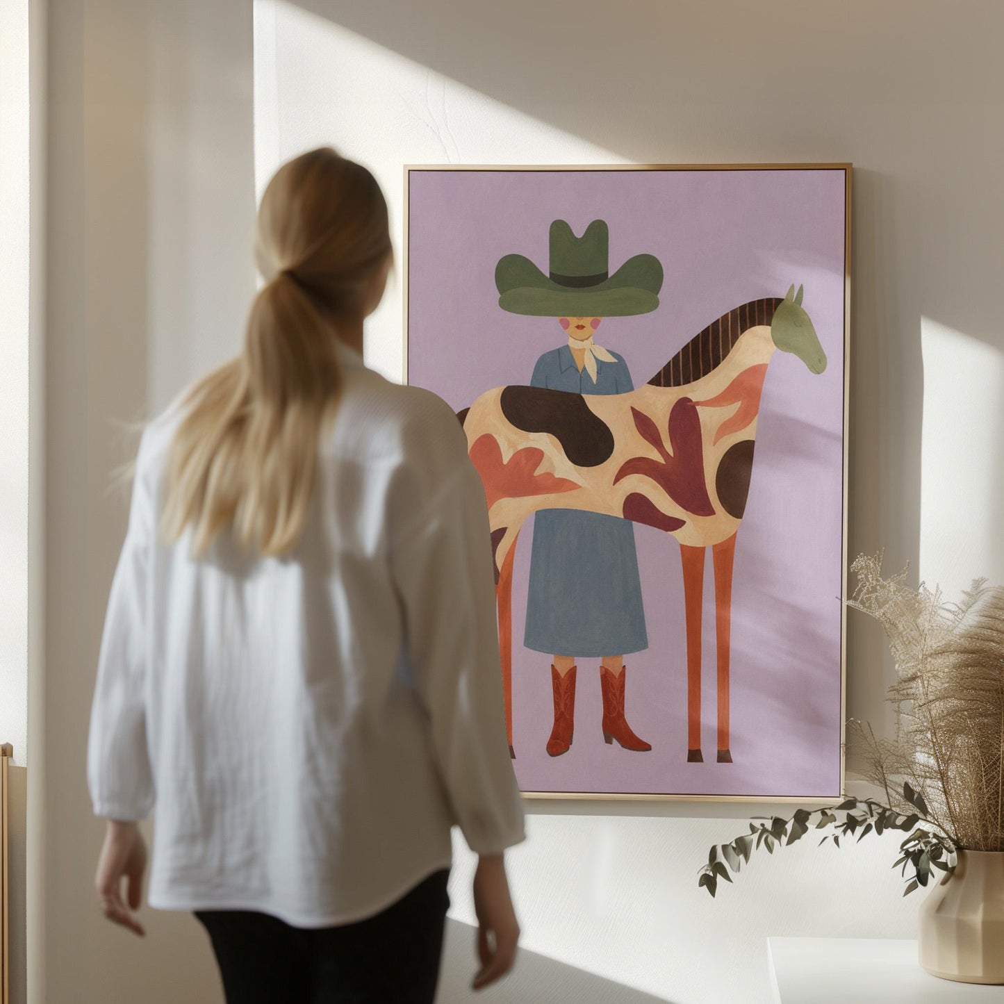 Cowgirl in a green hat beside a tall patterned horse on soft lilac, canvas print presented in a light, minimal room