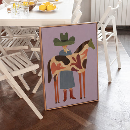 Cowgirl in a green hat beside a tall patterned horse on soft lilac, canvas wall art presented in a light, minimal room