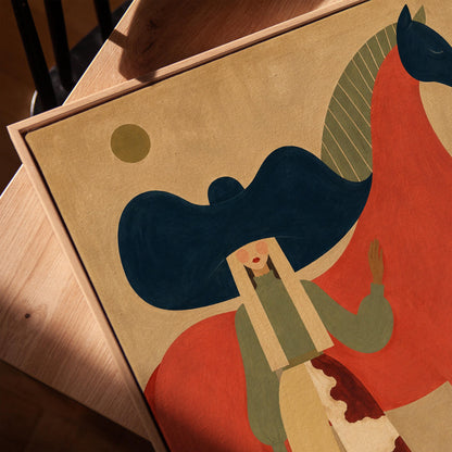 Woman in a big navy hat standing before a bright red horse on warm ochre, canvas print in a warm, minimally styled interior