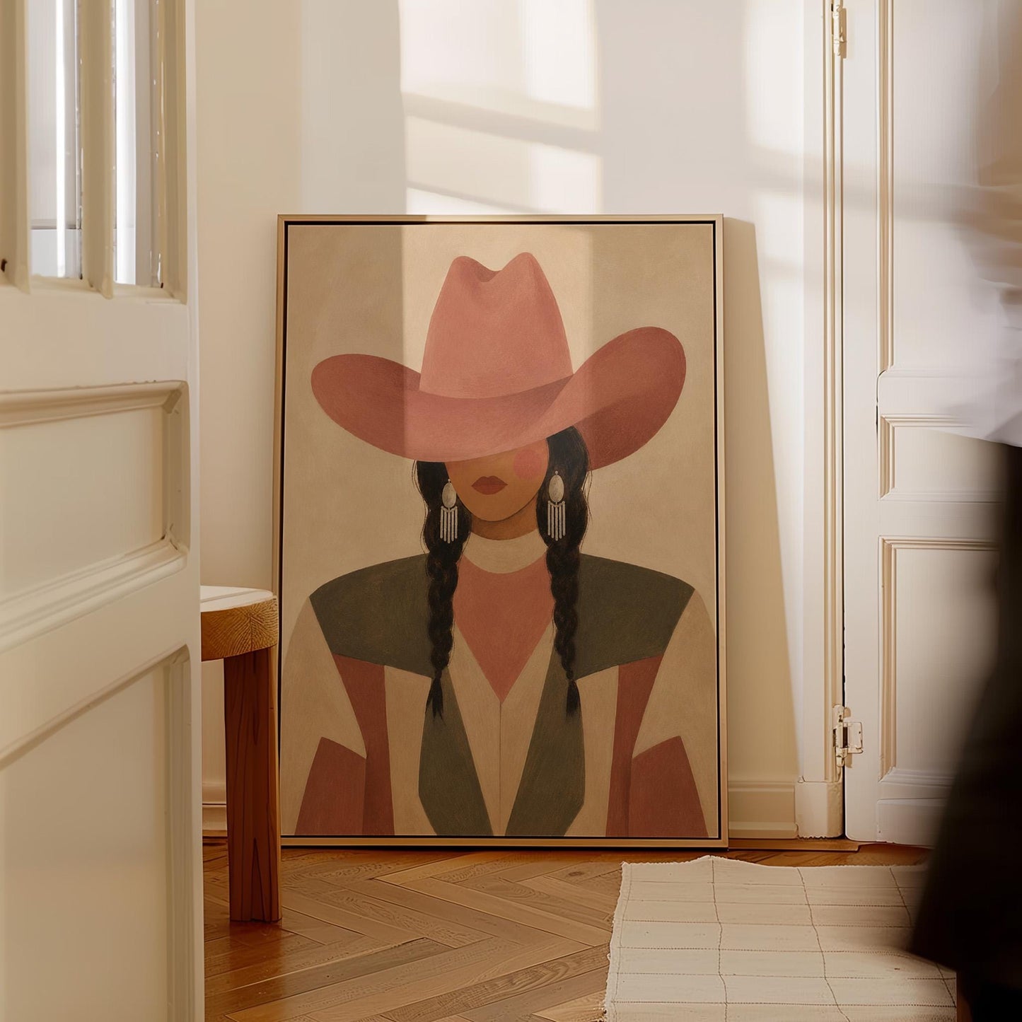 Cowgirl with dark braids under a wide terracotta hat and earthy western jacket, canvas wall art styled against a soft white wall
