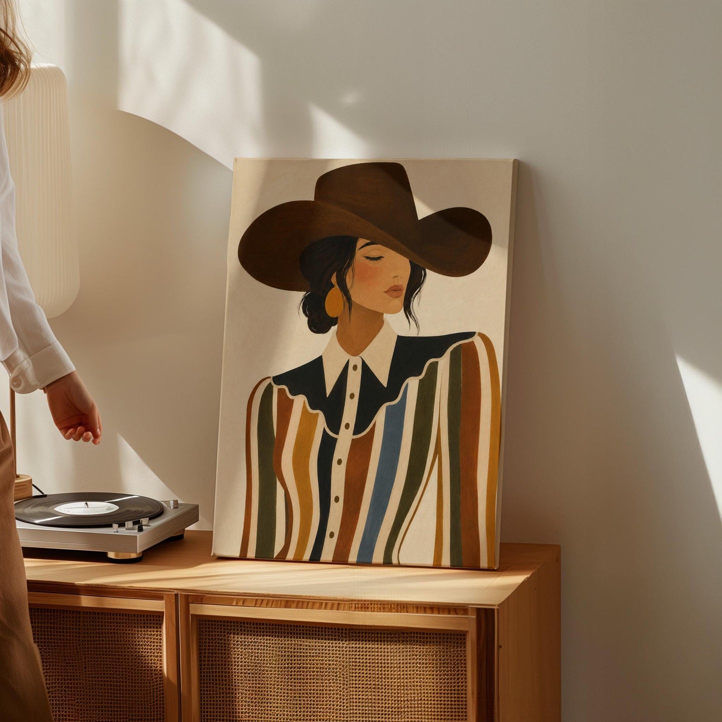 Cowgirl in a brown hat and rippling striped blouse with a black collar on cream, canvas print seen in a warm interior with natural light