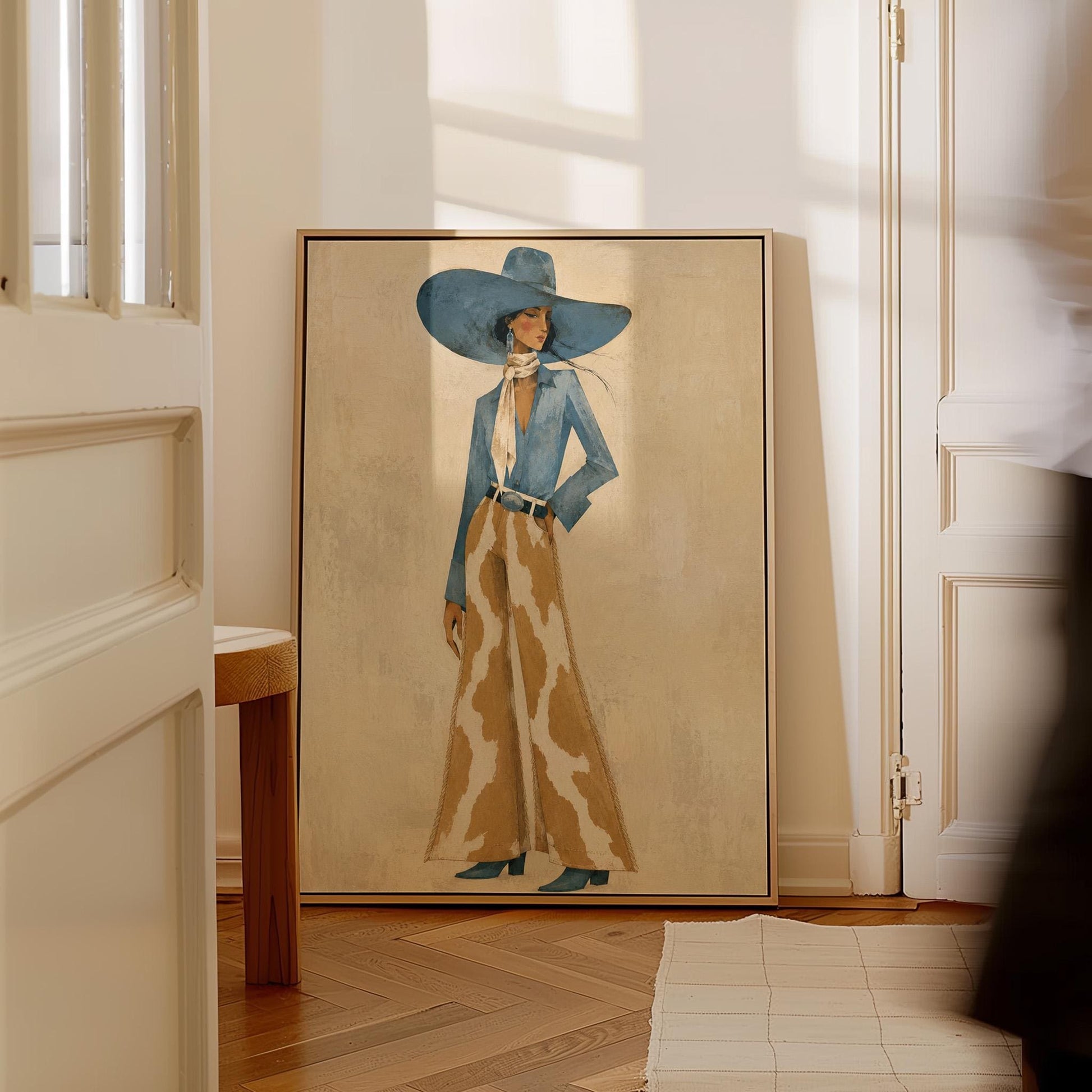Full-figure cowgirl in a blue hat, denim shirt and cow-print flared pants on cream, canvas print shown to scale in a furnished room