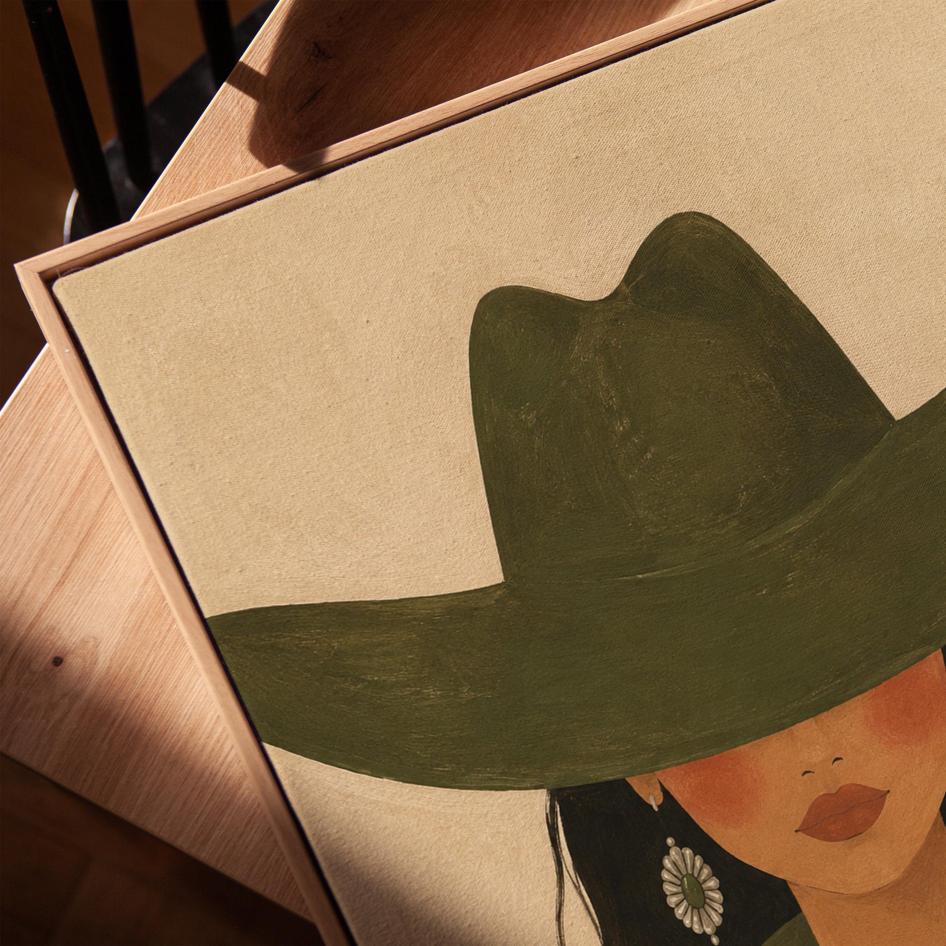 Cowgirl under a deep green hat with concho earrings and a striped western shirt, canvas print in a warm, minimally styled interior