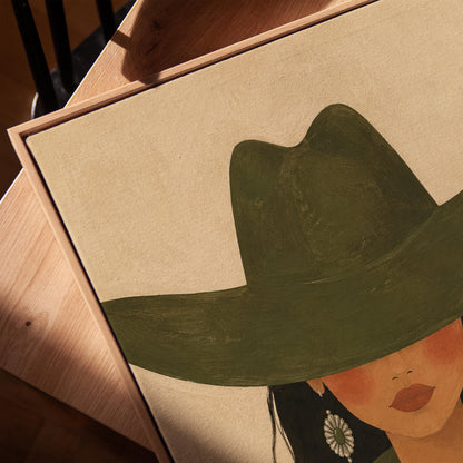 Cowgirl under a deep green hat with concho earrings and a striped western shirt, canvas print in a warm, minimally styled interior