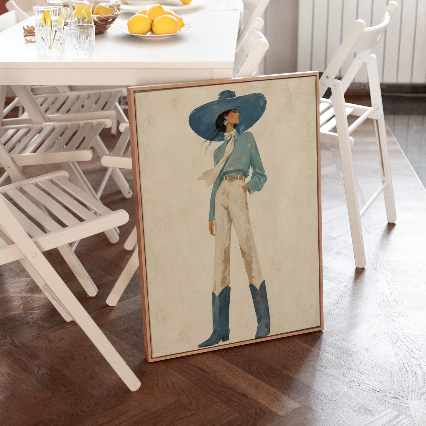 Full-figure cowgirl in a wide teal hat, blouse and boots with cream trousers, canvas print seen in a warm interior with natural light