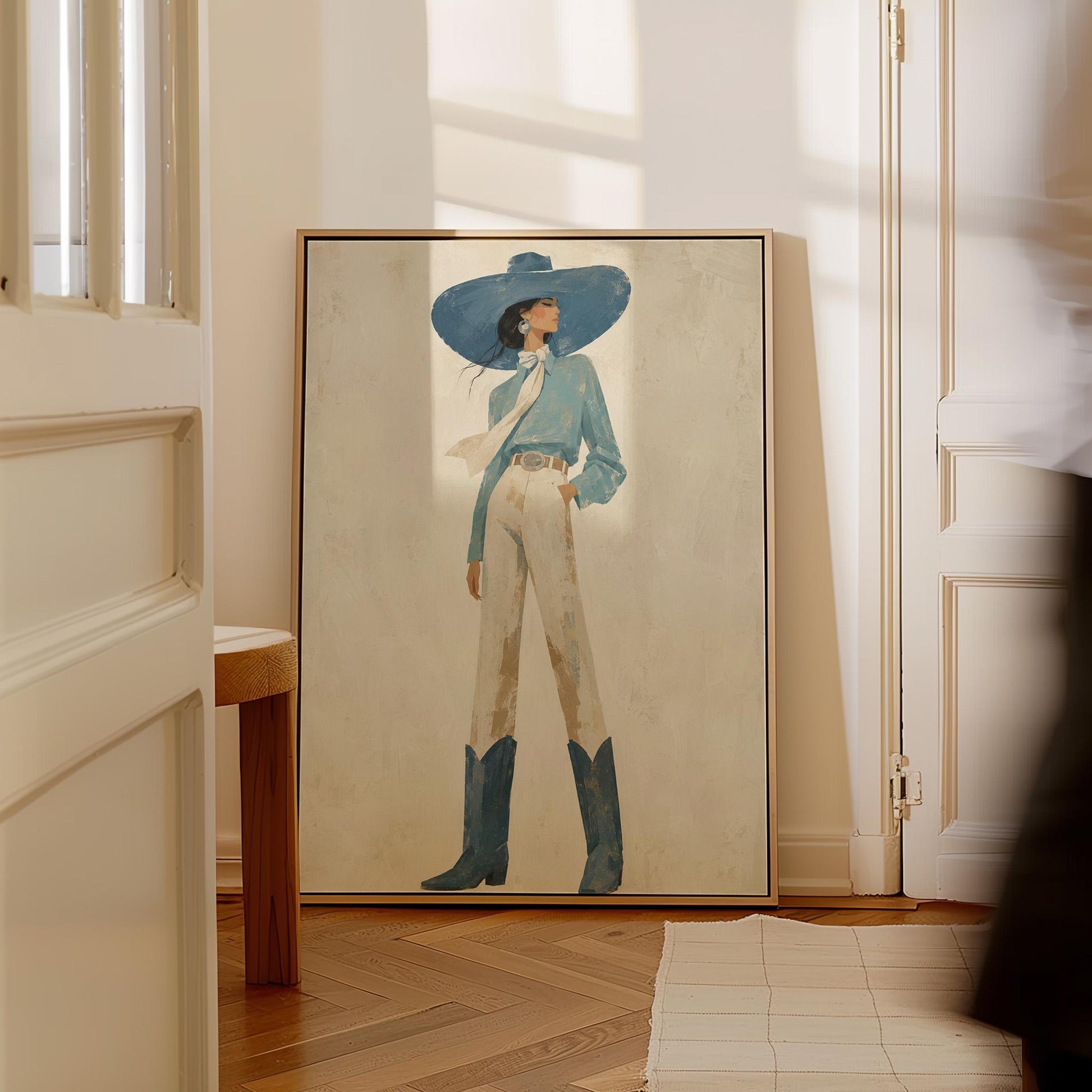 Full-figure cowgirl in a wide teal hat, blouse and boots with cream trousers, canvas print presented in a light, minimal room
