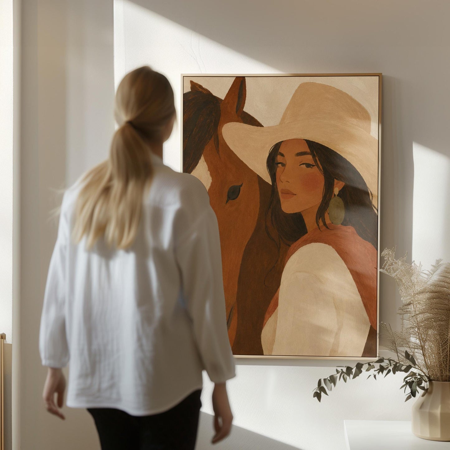 Cowgirl in a cream hat leaning cheek to cheek with a chestnut horse on warm tan, canvas wall art hanging in a calm, modern living space