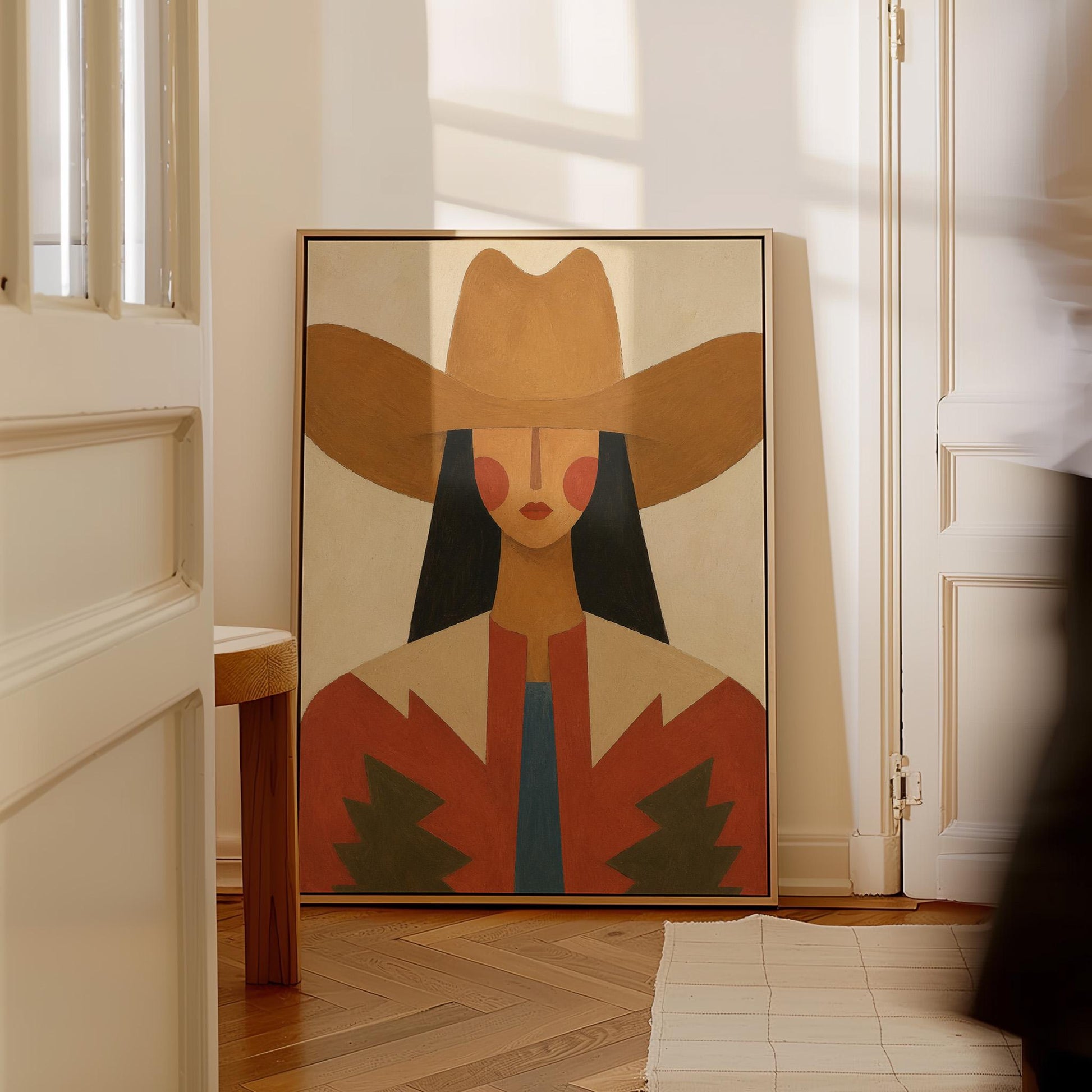 Folk cowgirl in a tan hat with rosy cheeks and a red aztec jacket on cream, canvas print on a quiet wall in a considered interior