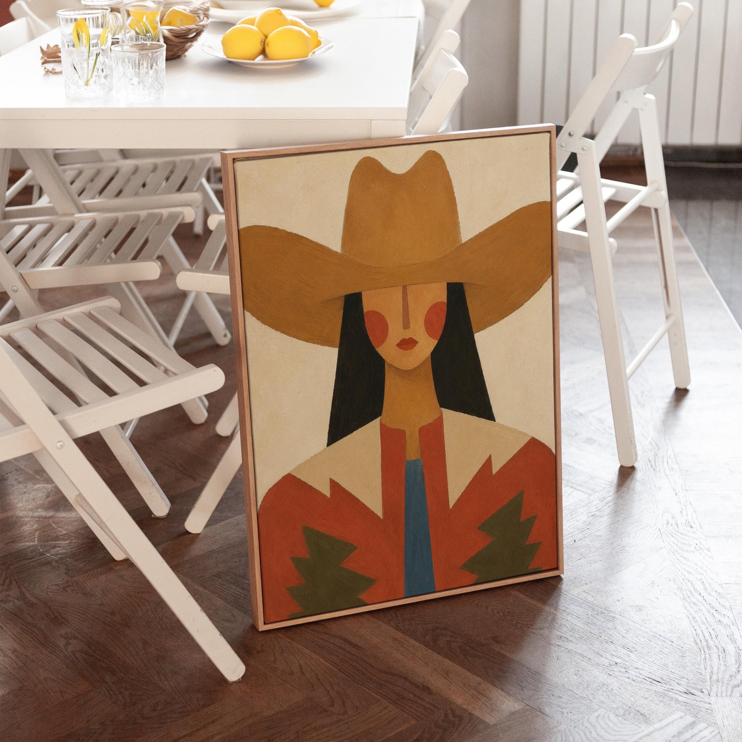 Folk cowgirl in a tan hat with rosy cheeks and a red aztec jacket on cream, canvas wall art on a quiet wall in a considered interior