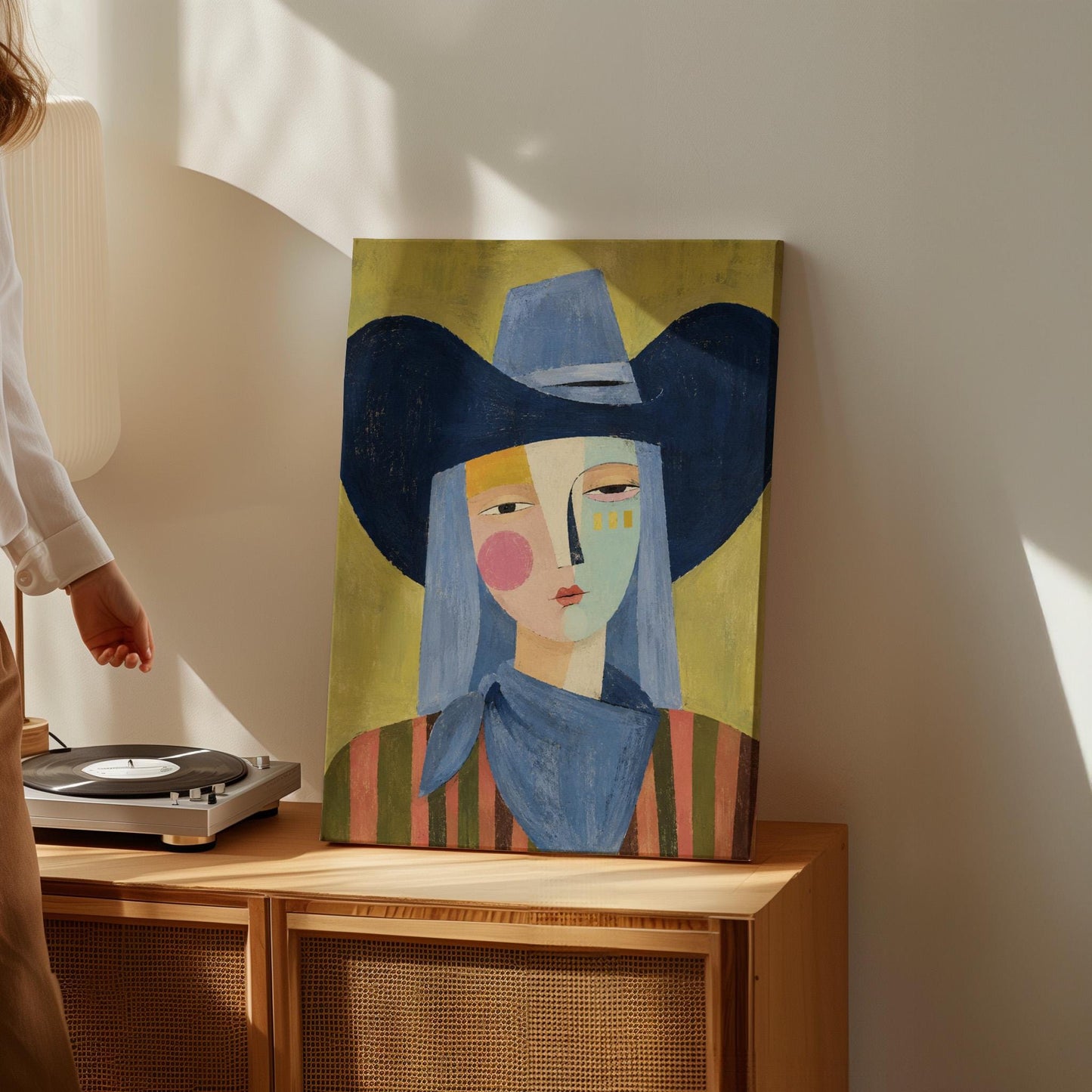 Cubist cowgirl with a big navy hat and multicolor face on olive yellow, canvas wall art hanging in a calm, modern living space
