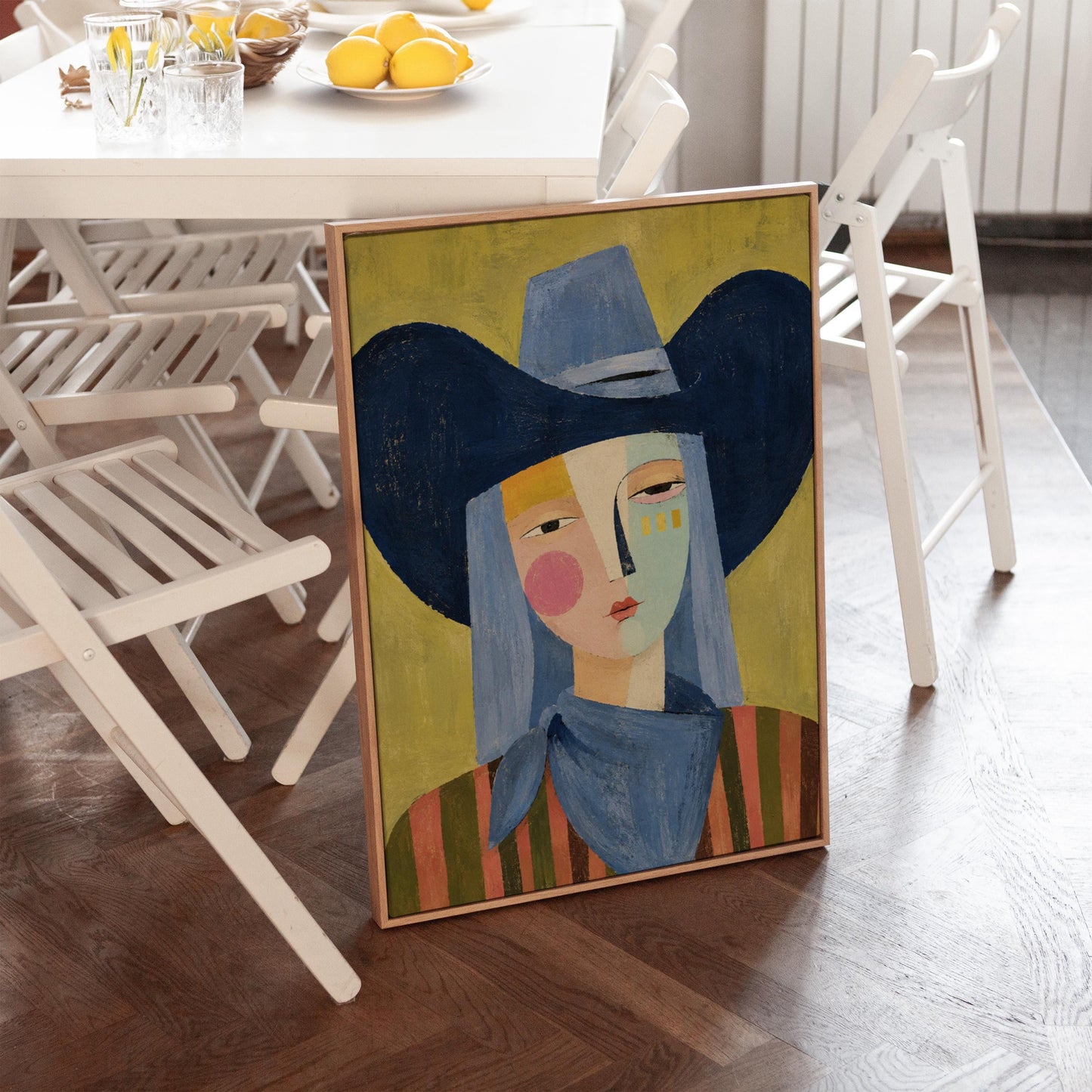 Cubist cowgirl with a big navy hat and multicolor face on olive yellow, canvas wall art on a quiet wall in a considered interior