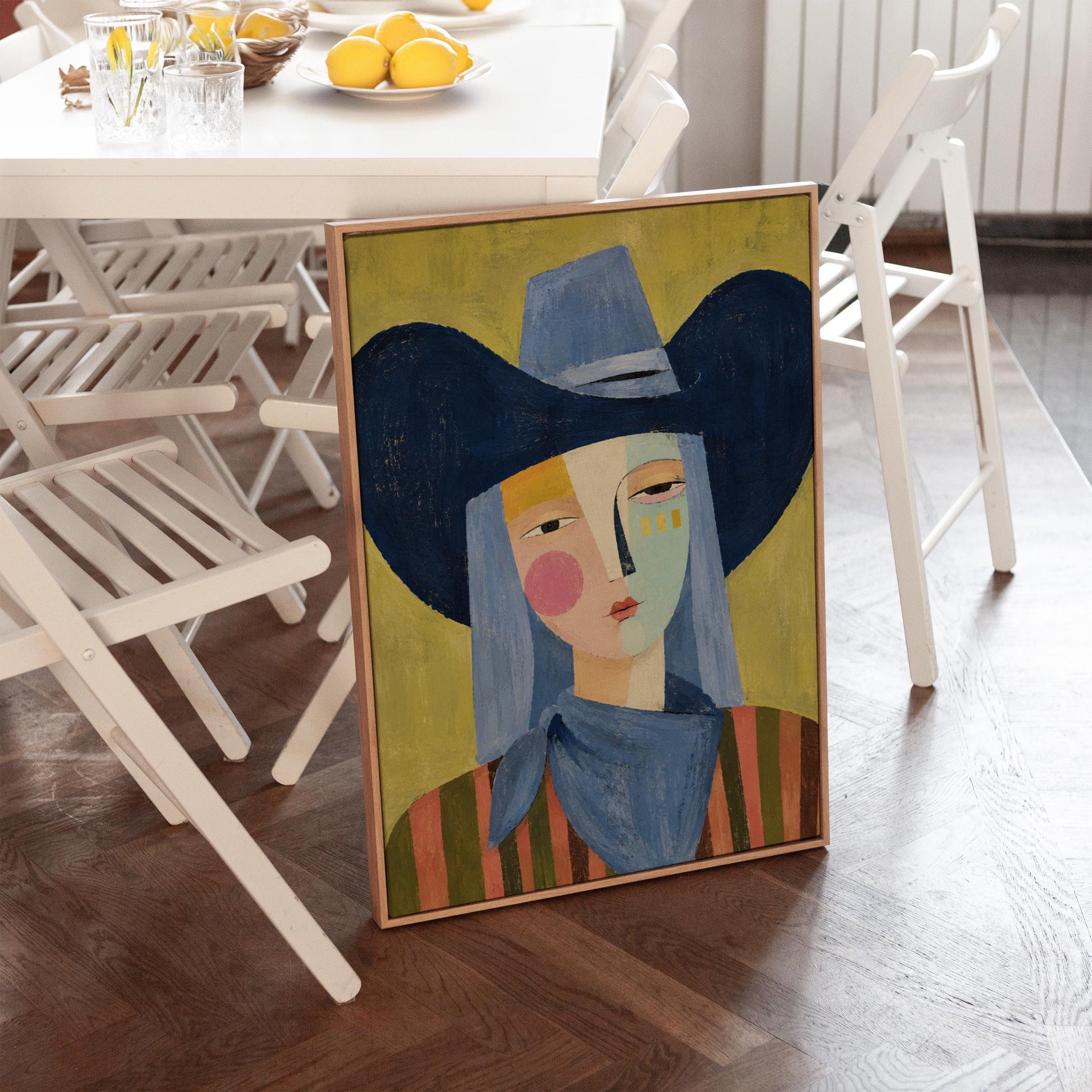 Cubist cowgirl with a big navy hat and multicolor face on olive yellow, canvas wall art on a quiet wall in a considered interior