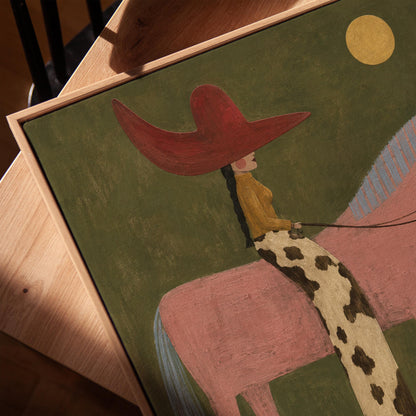 Cowgirl in a red hat riding a tall pink horse past a cactus under the moon, canvas print in a warm, minimally styled interior