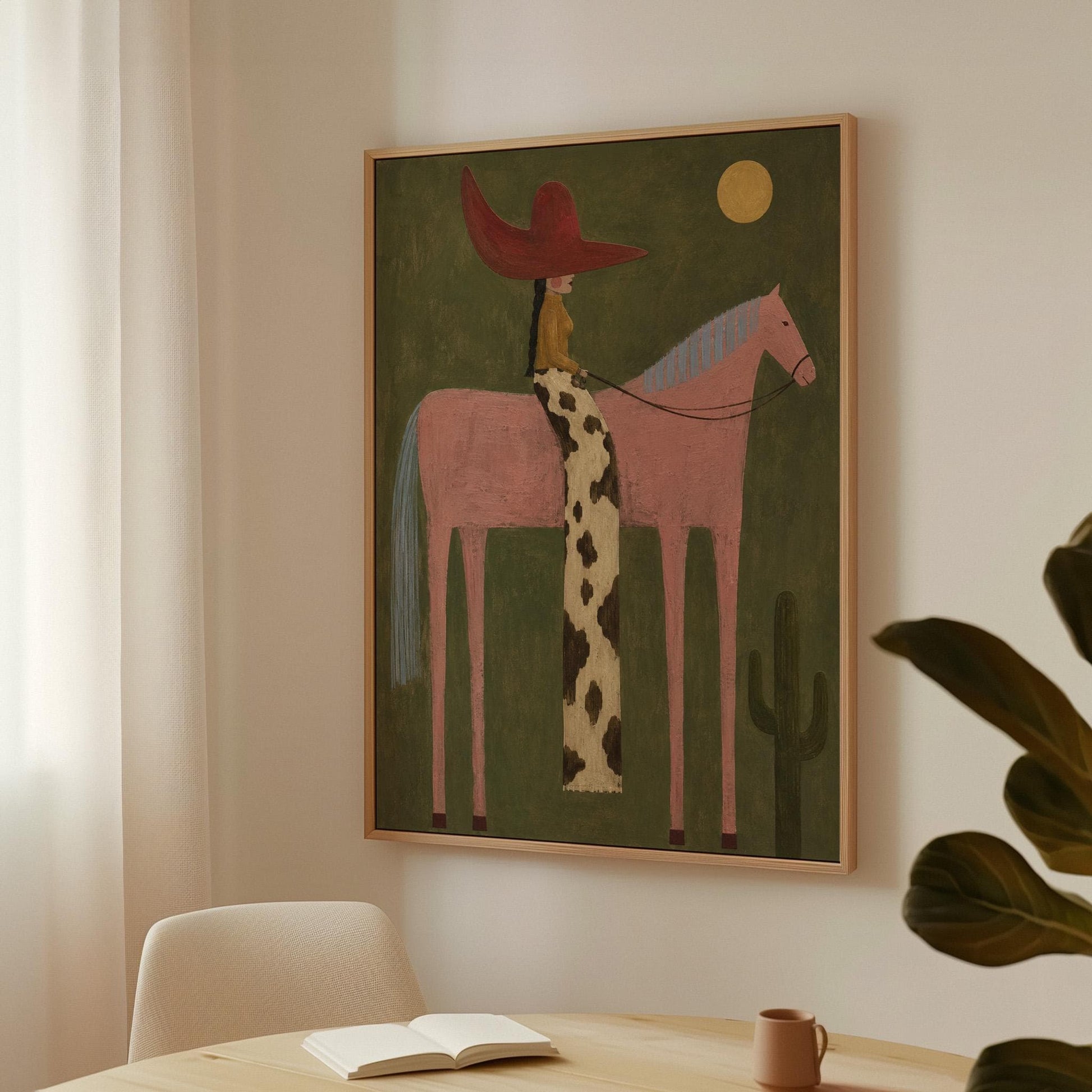 Cowgirl in a red hat riding a tall pink horse past a cactus under the moon, canvas print displayed on a neutral wall in a styled interior