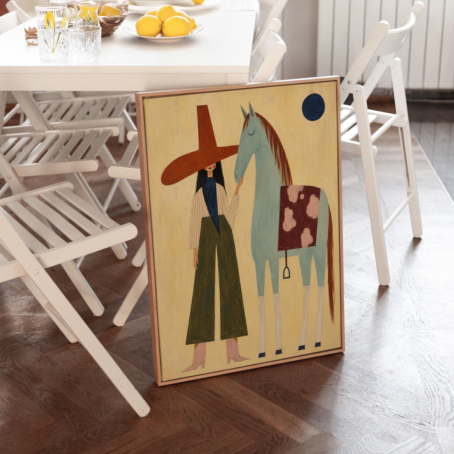 Woman in a wide red hat standing beside a gentle blue horse in the desert, canvas wall art presented in a light, minimal room