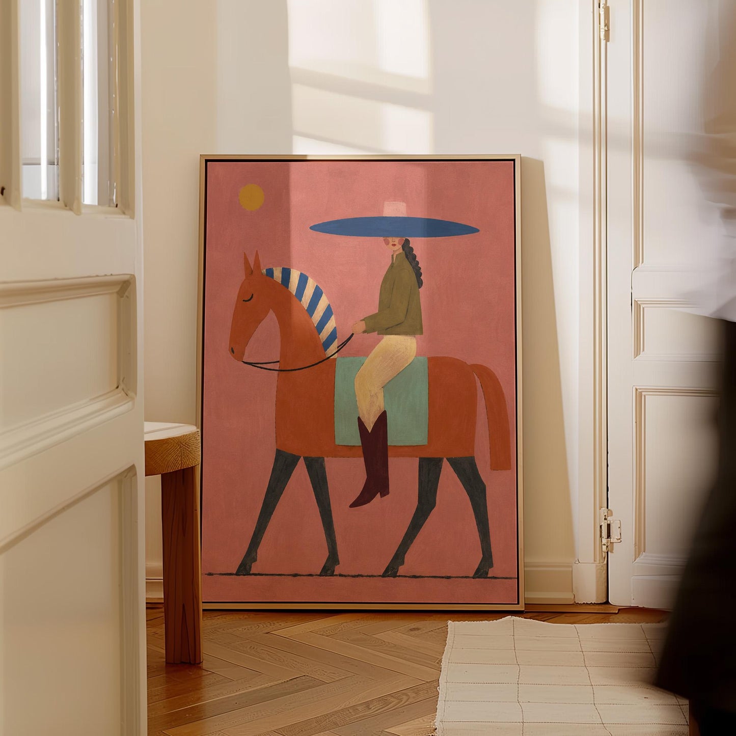 Cowgirl in a broad blue hat riding a rust red horse across a coral sky, canvas wall art on a quiet wall in a considered interior