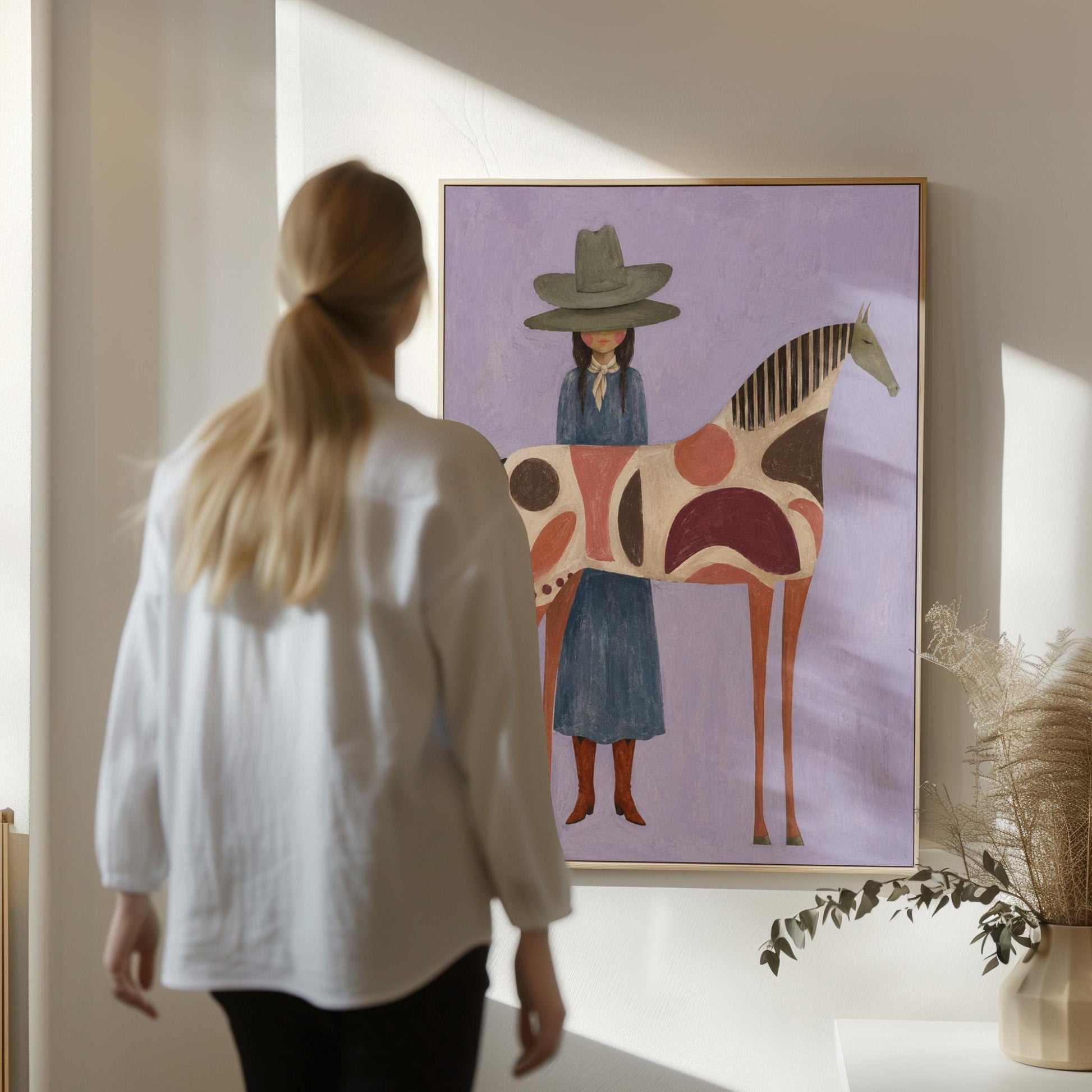 Woman in an olive hat before a patterned folk horse on a lavender ground, canvas print shown in a sunlit, contemporary room