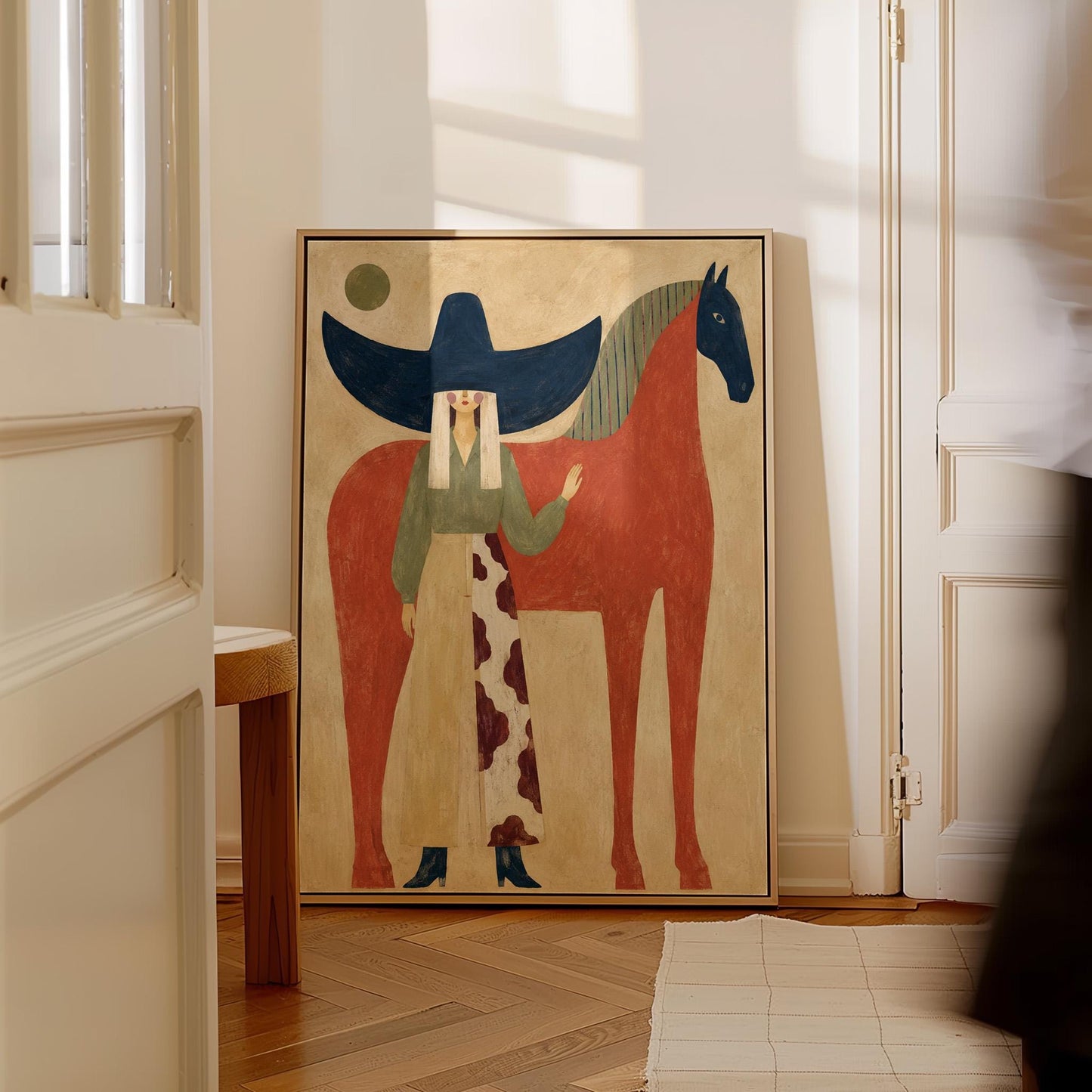 Woman in a navy hat standing by a red horse with a dark head under a moon, canvas print hanging in a calm, modern living space