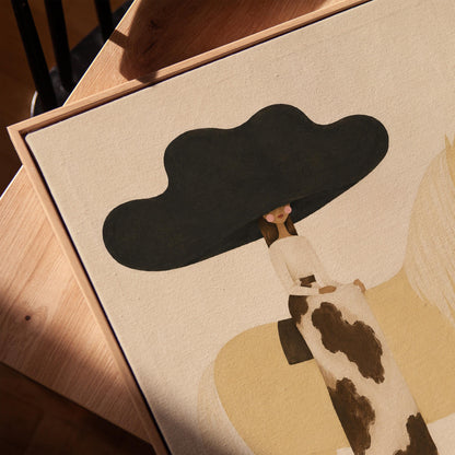 Woman in a huge black hat riding a pale palomino across a desert with cactus, canvas print in a warm, minimally styled interior
