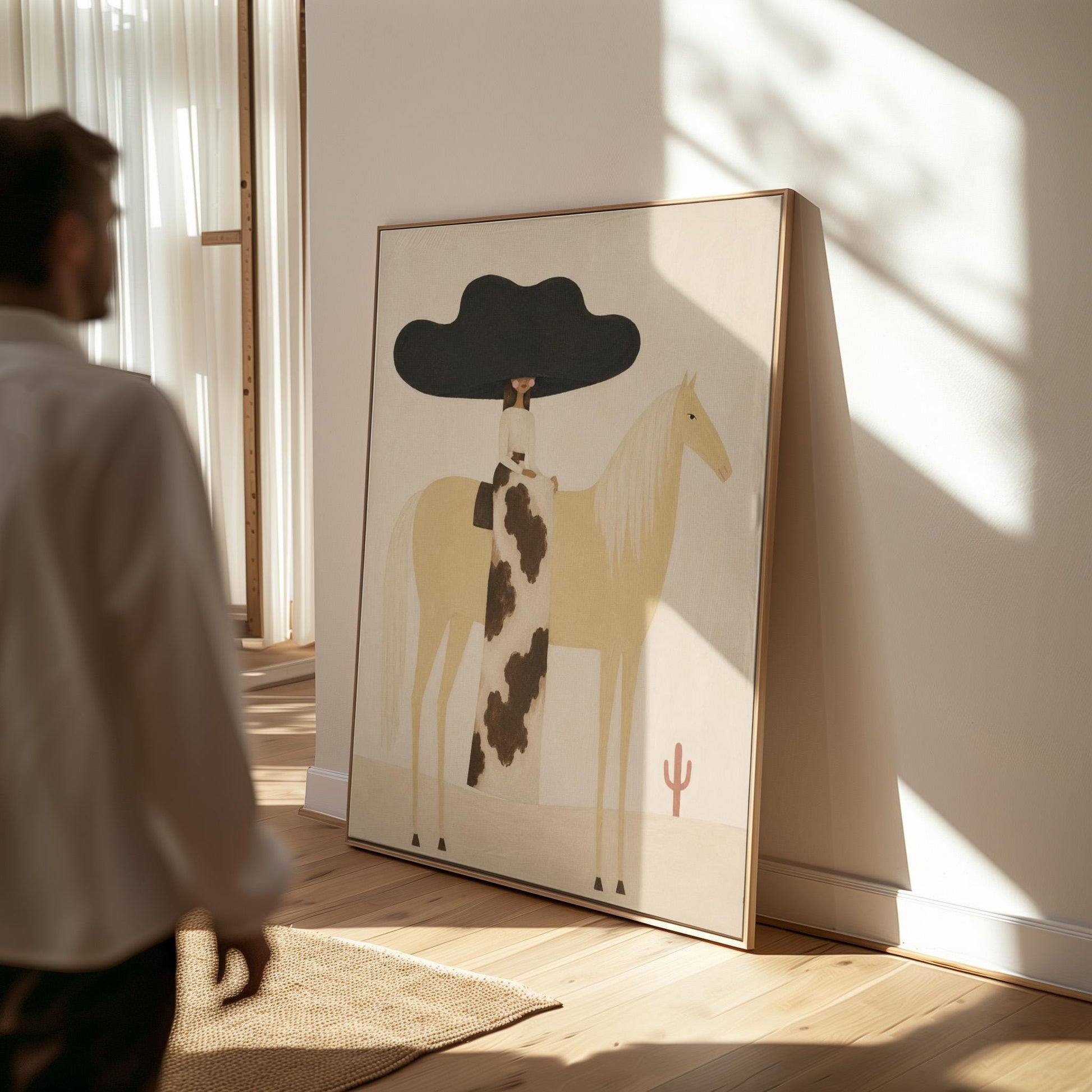 Woman in a huge black hat riding a pale palomino across a desert with cactus, canvas wall art on a quiet wall in a considered interior