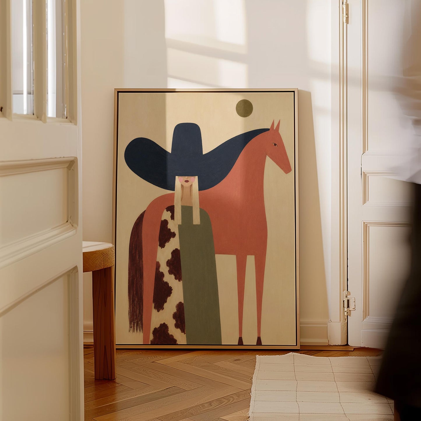 Cowgirl in a black sombrero and cow print cape beside a rust red horse, canvas print seen in a warm interior with natural light