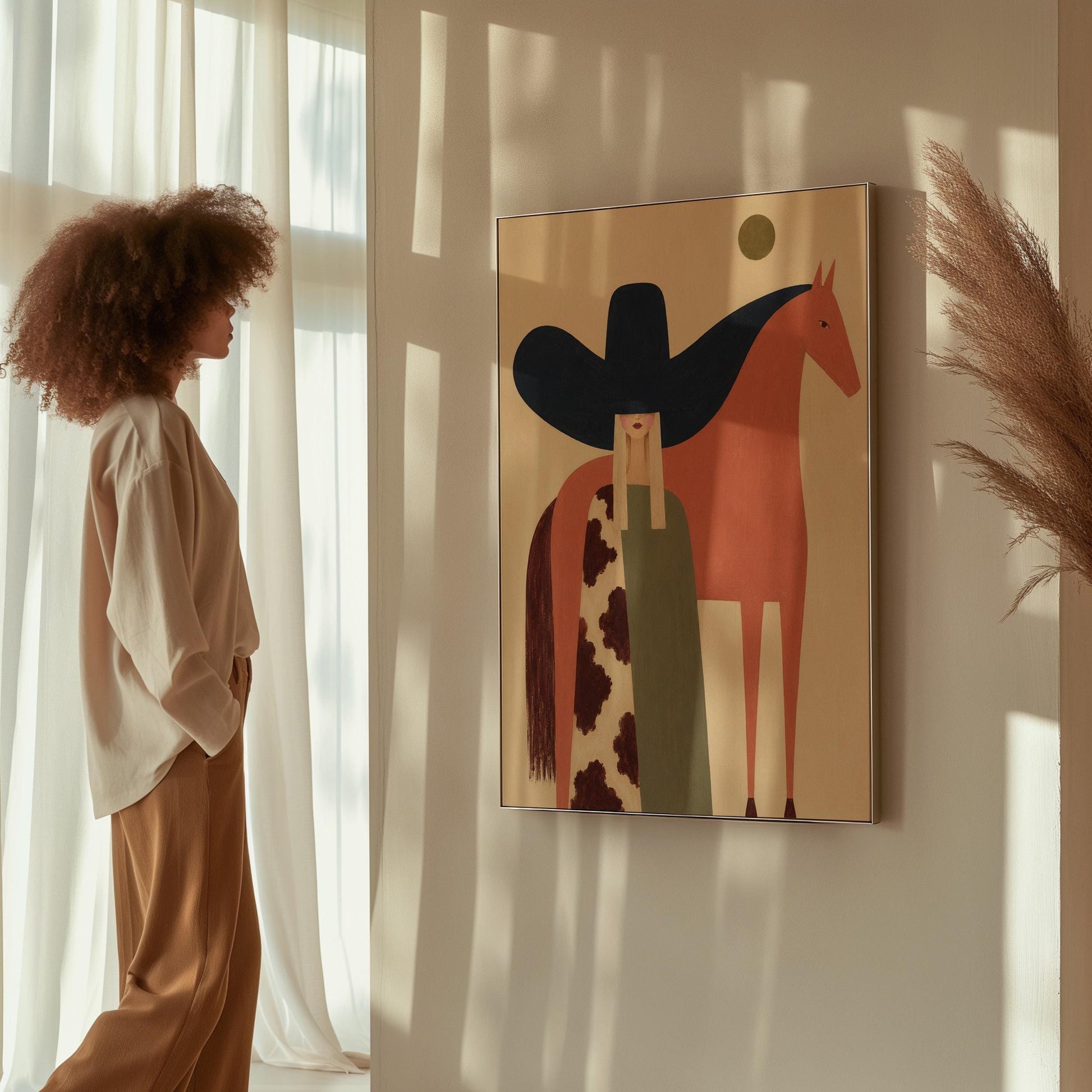 Cowgirl in a black sombrero and cow print cape beside a rust red horse, canvas wall art on a quiet wall in a considered interior