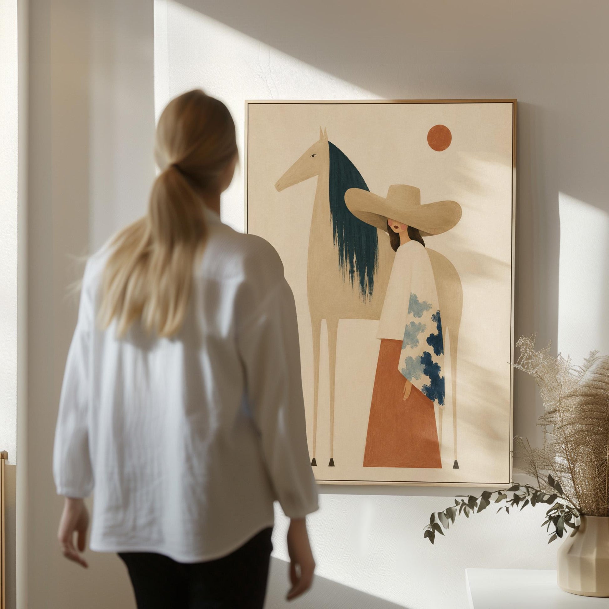 Woman in a broad tan hat beside a cream horse with a teal mane at sunset, canvas print presented in a light, minimal room