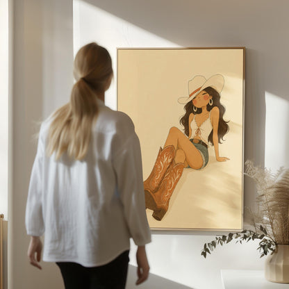 Cowgirl in denim shorts and cowboy boots leaning back under a wide pale hat, canvas wall art styled against a soft white wall