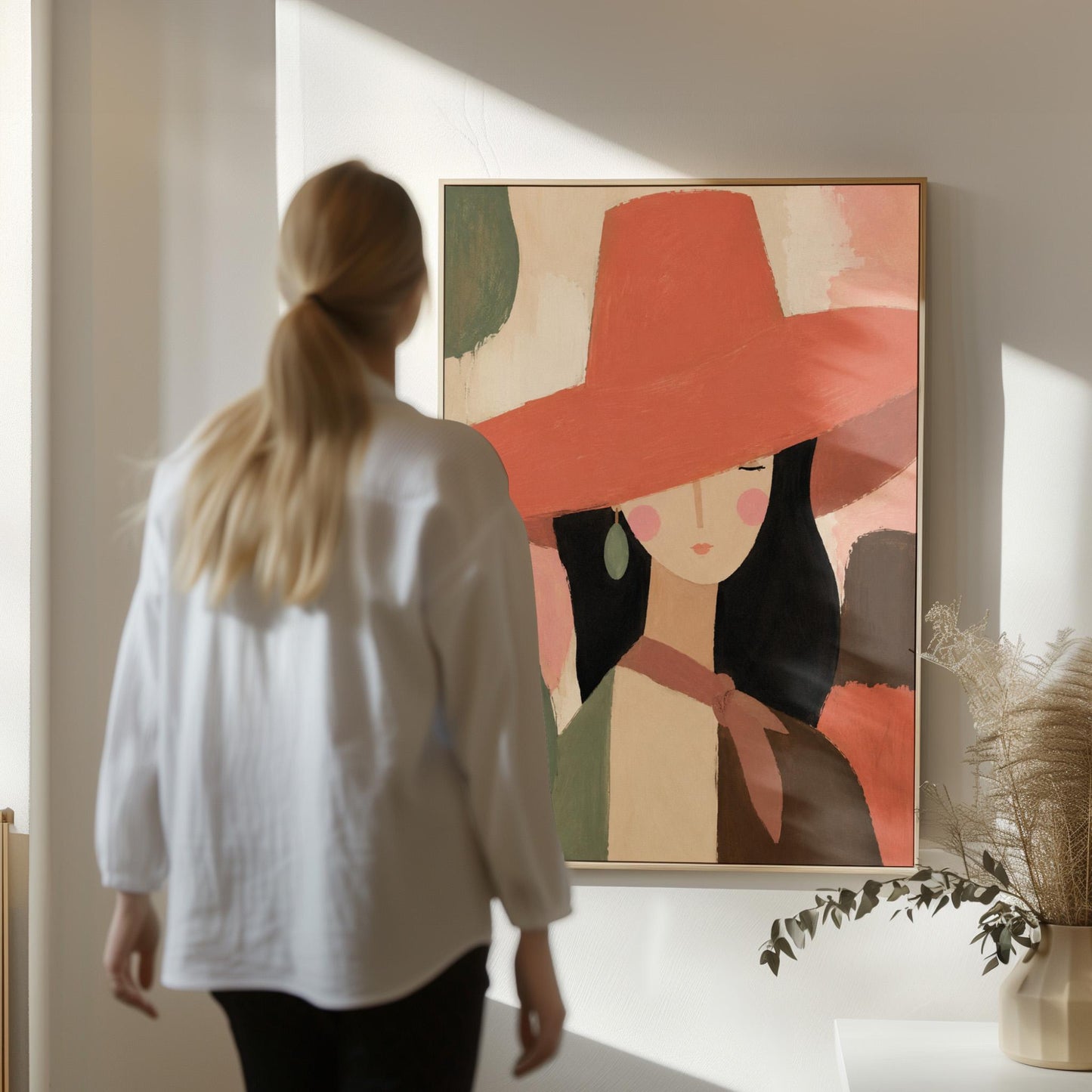 Woman in a wide coral hat with jade earring on blocked color, canvas wall art presented in a light, minimal room