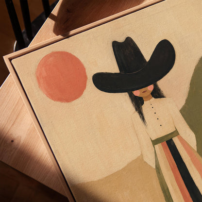 Figure in black cowboy hat standing between coral desert hills, canvas print in a warm, minimally styled interior
