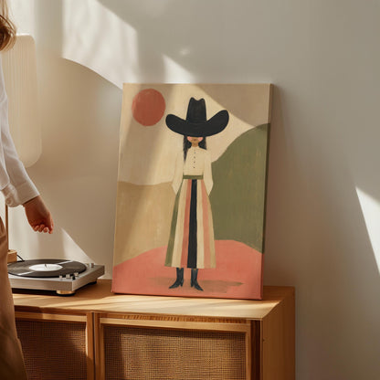 Figure in black cowboy hat standing between coral desert hills, canvas print presented in a light, minimal room