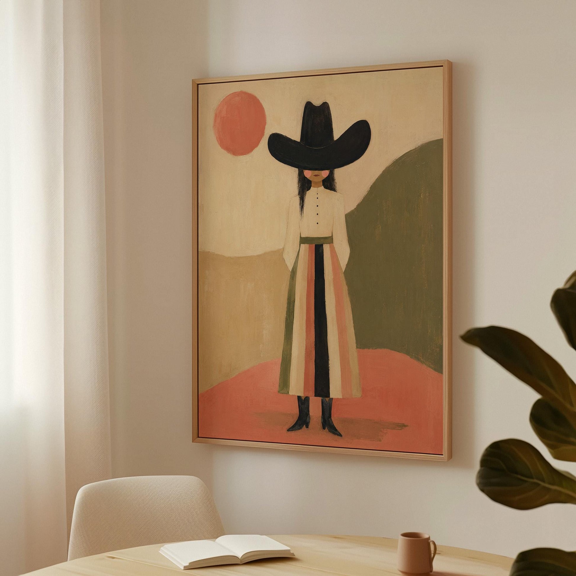 Figure in black cowboy hat standing between coral desert hills, canvas print shown in a sunlit, contemporary room