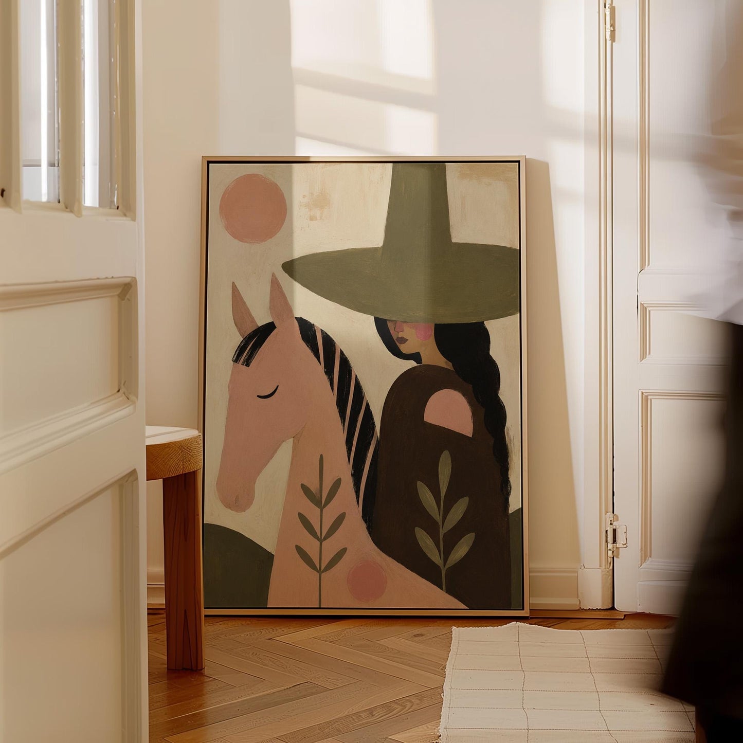 Pink horse beside a cowgirl in an olive hat with leaf motifs, canvas print shown to scale in a furnished room