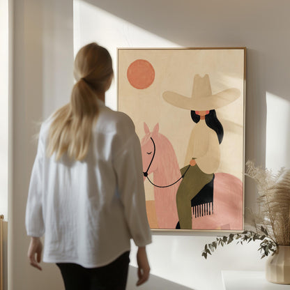 Cowgirl in a pale hat riding a soft pink horse past a desert cactus, canvas print on a quiet wall in a considered interior
