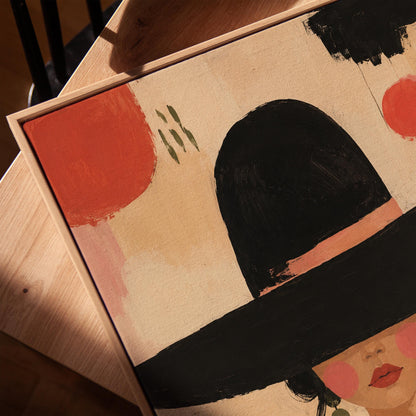 Woman in a wide black hat with olive earrings on red brushwork, canvas print in a warm, minimally styled interior