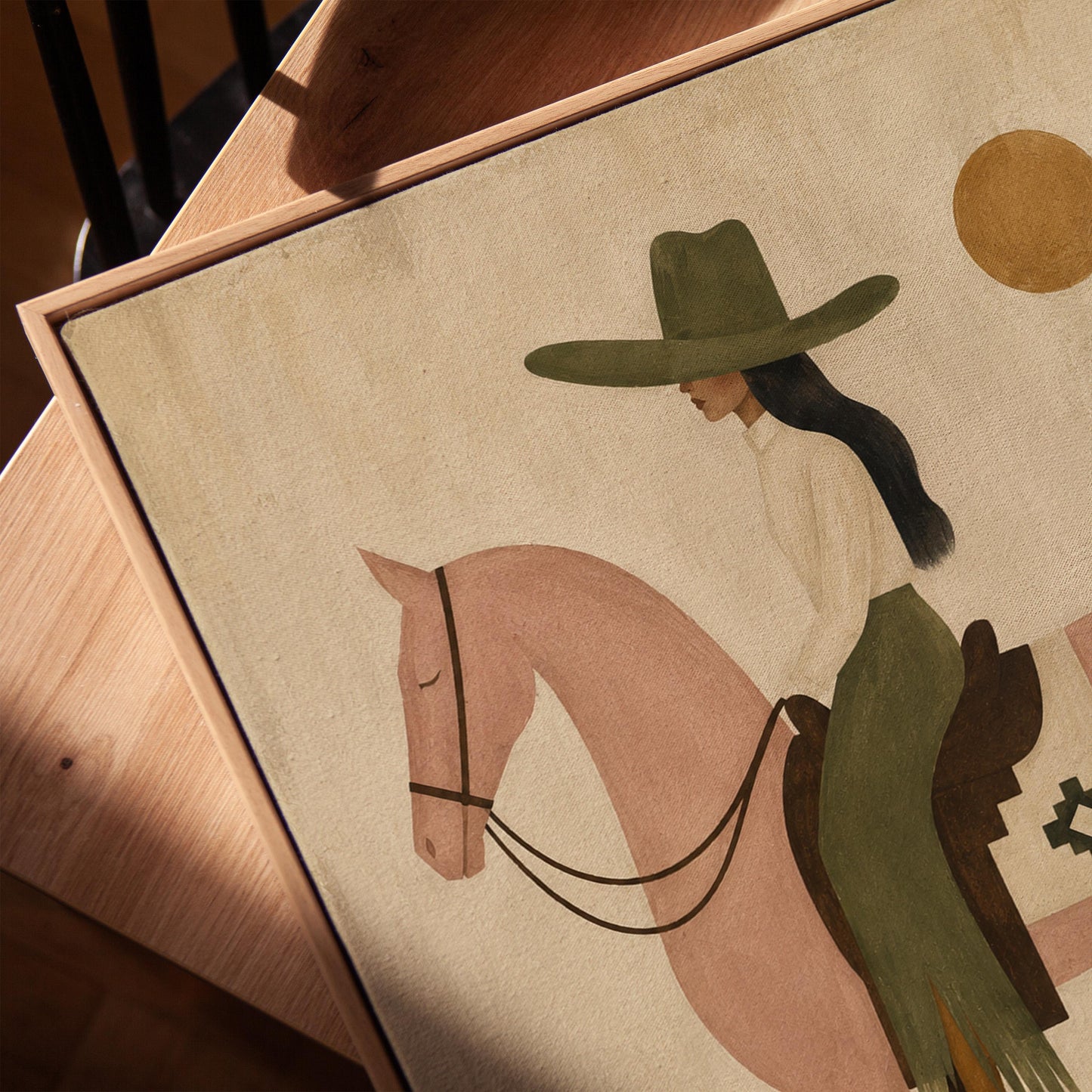 Cowgirl on a dusty pink horse beside a tall saguaro cactus, canvas print in a warm, minimally styled interior