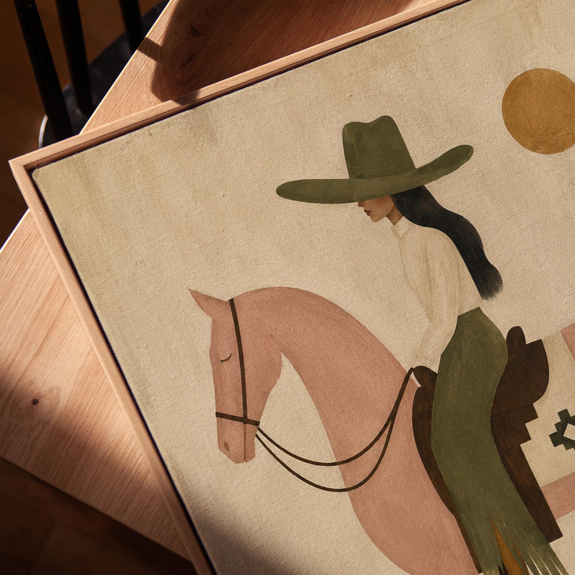 Cowgirl on a dusty pink horse beside a tall saguaro cactus, canvas print in a warm, minimally styled interior