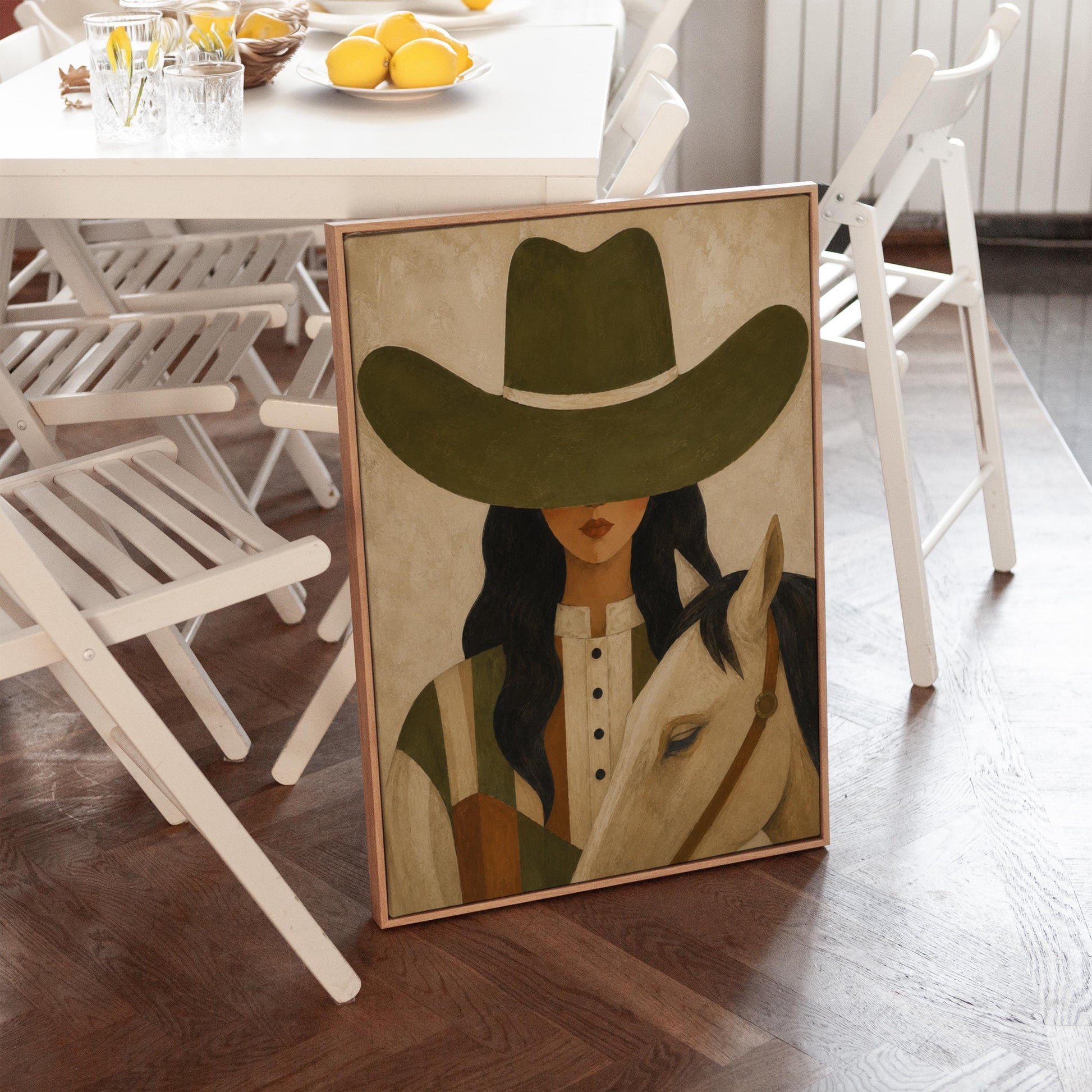 Cowgirl in an olive hat leaning close to a pale white horse, canvas print shown to scale in a furnished room